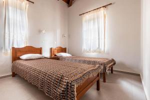 two beds in a room with two windows at Porto Kalamitsi Stone-built Bungalows in Kardamili