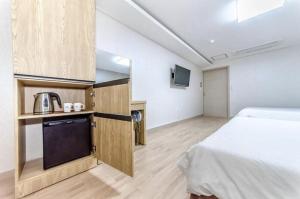 um quarto com uma cama e uma cozinha com um micro-ondas em SH Jungmoon City Stay em Seogwipo