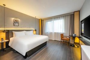 una camera d'albergo con un grande letto e una TV di UrCove by HYATT Shanghai Jinqiao Centre a Shanghai