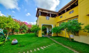 uma casa amarela com um quintal em frente em Visalam Chettinad Palace - CGH Earth em Chettinadu