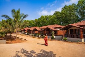 a woman in a red dress standing in front of a row of houses at Zostel Gokarna in Gokarna