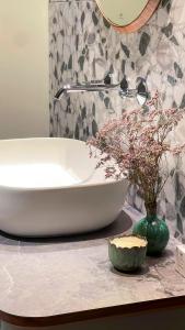 a bathroom with a sink and a vase of flowers on a counter at Auberge Pom'Poire in Azay-le-Rideau