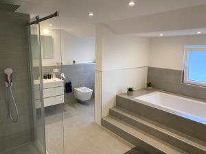 a bathroom with a tub and a toilet and a sink at Ermmes Ferienwohnungen in Sinsheim