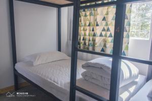 1 dormitorio con litera con sábanas y almohadas blancas en Kaiping Tangkou Village Inn, en Jiangmen