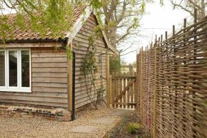 a wooden fence next to a house with a gate at Mustard Pot Cottage in Eye