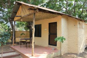 une petite maison avec une table et des chaises sur une terrasse couverte dans l'établissement Avadale Tadoba - Stag Groups Not Allowed, à Mohurli