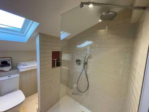 uma casa de banho com um chuveiro, um WC e uma janela. em Mustard Pot Cottage em Eye