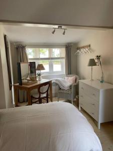 a bedroom with a bed and a desk and a window at Mustard Pot Cottage in Eye