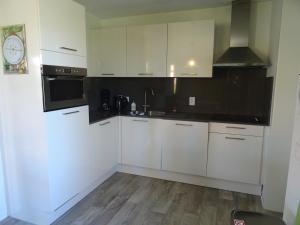 a white kitchen with a sink and a microwave at Kustverhuur, Landgoed de Lente in Breskens