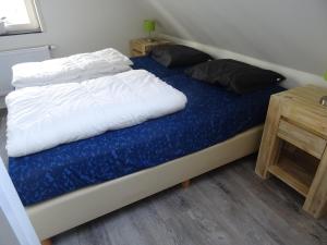 a bed with a blue blanket and two pillows on it at Kustverhuur, Landgoed de Lente in Breskens