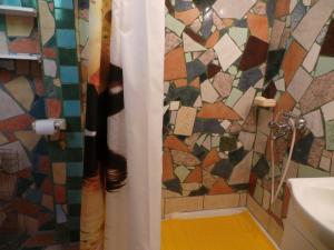 a bathroom with a shower curtain and a mosaic wall at 2 L in Jablanac