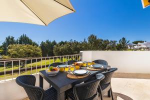 a table with chairs on a balcony with food on it at Apartament Portes Balaia in Albufeira