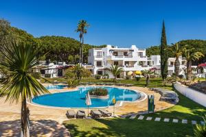 a swimming pool in front of a large white house at Apartament Portes Balaia in Albufeira