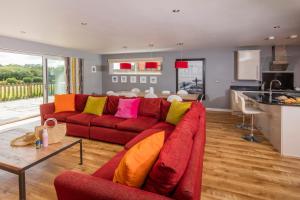 a living room with a red couch with colorful pillows at PointBreak Sleeps 12 with hot tub-Great celebration house-Dog friendly in Padstow