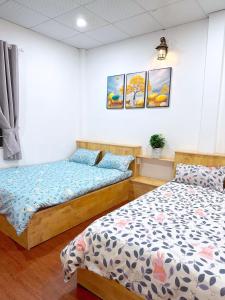 1 dormitorio con 2 camas y 2 cuadros en la pared en Suri's House Homestay, en Da Lat