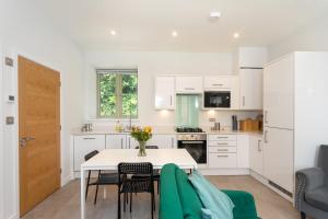 uma cozinha com armários brancos e uma mesa e cadeiras em Beautiful Honeycomb Cottage in heart of Cotswolds em Chipping Norton