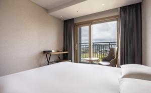 um quarto de hotel com uma cama e uma janela em SH Golden Tulip Seongsan Stay em Seogwipo