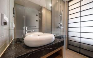 a bathroom with a white sink on a counter at SH Golden Tulip Seongsan Stay in Seogwipo