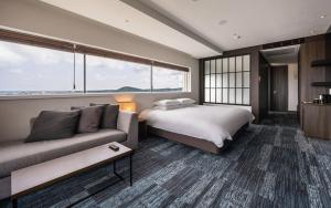 une chambre d'hôtel avec un lit et un canapé dans l'établissement SH Golden Tulip Seongsan Stay, à Seogwipo