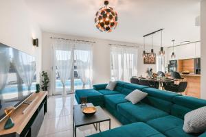 sala de estar con sofá azul y comedor en La Reina House - Private Heated Pool en Bibinje