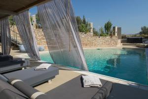 a swimming pool with two chaise lounges next to at AVAL Riviera in Lagonissi