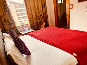 a bedroom with a bed with a red blanket and a window at WooibHotels The Solitaire in Manāli