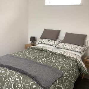 a bed with a black and white blanket and pillows at Rockpool - Bude in Bude