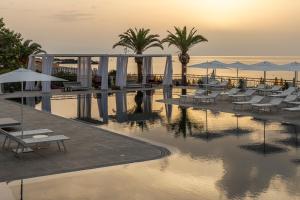 - une piscine avec des chaises et des parasols dans un complexe dans l'établissement Delta Hotels by Marriott Giardini Naxos, à Giardini Naxos