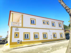 a yellow and white building on the side of a street at Casa Mar Azul in Vila Nova de Milfontes