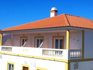 un edificio con balcón y techo rojo en Casa Mar Azul, en Vila Nova de Milfontes