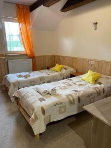 2 camas en una habitación con cortinas naranjas en Folwark Tumiany Pokoje & Restauracja en Tumiany