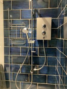 a shower in a bathroom with a blue tiled wall at Rockpool - Bude in Bude