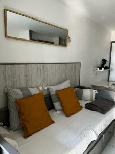uma cama com duas almofadas laranja e um espelho em Chez Mag et Jo em Moliets-et-Maa