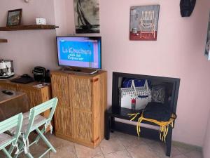un soggiorno con TV, tavolo e sedie di Casa Teria a Villasimius