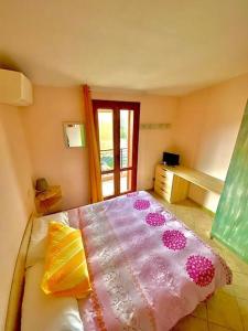 a bedroom with a bed with a pink blanket and a window at Casa Teria in Villasimius