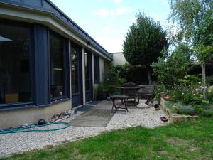 eine Terrasse eines Hauses mit einem Tisch und Stühlen in der Unterkunft Chambre d'hôtes sur jardin acces PMR in Caen