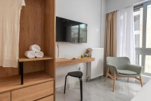 塞薩羅尼基的住宿－ΙΩΚΑ Suites / the Urbitality Project，客房设有电视、椅子和书桌。
