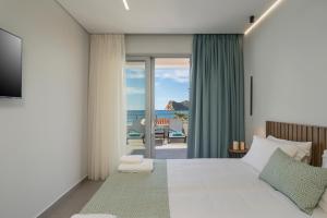 a bedroom with a bed and a view of the ocean at Ostrakon Suites in Agia Marina Nea Kydonias