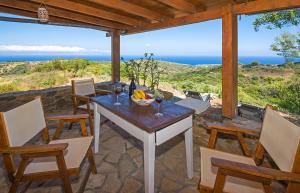 a table and chairs on a patio with a view of the ocean at Two little houses with panorama view in Kýthira