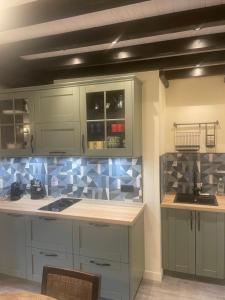a kitchen with green cabinets and blue tiles at Nid douillet in Pont-Audemer +12 photos