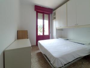 1 dormitorio con cama blanca y puerta roja en Lido, en Lido delle Nazioni