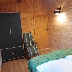 ein Schlafzimmer mit einem Bett, einem Stuhl und einer Tür in der Unterkunft Domki Na Winnicy - Winnica Talaska 