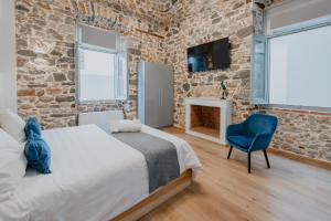 a bedroom with a brick wall and a bed and a chair at Impero Nafplio Hotel & Suites in Nafplio