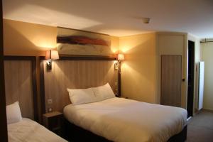 a hotel room with two beds and two lamps at Logis Lhôtel Restaurant Antony Verrières Le Buisson in Verrières-le-Buisson