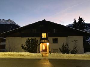 uma casa com uma porta iluminada na neve em Tga Rundigna em Savognin