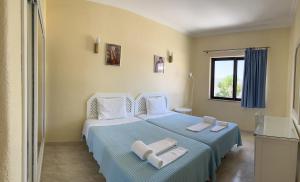 a bedroom with a blue bed with towels on it at FLOR DO VALE - APARTAMENTOS TURISTICOS in Guia +27 photos