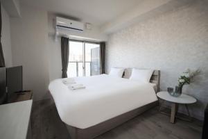 a bedroom with a large white bed and a table at Seiryu Tsutenkaku in Osaka