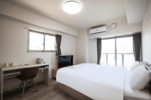 1 dormitorio con cama blanca, escritorio y ventana en Seiryu 通天閣 en Osaka