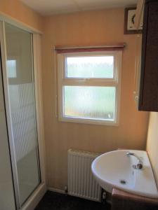 a bathroom with a sink and a window and a shower at 6 Berth Sealands Ingoldmells Central heated (Carlton) in Ingoldmells