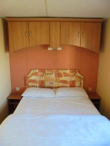 a bedroom with a bed with a wooden headboard at 6 Berth Sealands Ingoldmells Central heated (Carlton) in Ingoldmells
